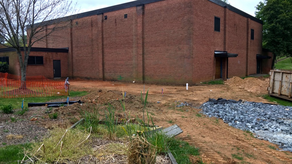 The low wall and patio on the Ablewood Road end of the buildng have been been removed. The 2014 renovation plans called for an extension of the low building across the front of the gym, to create another meeting room. The brown door at left is the same one shown behind the plumbing already installed in the center of the old game room.