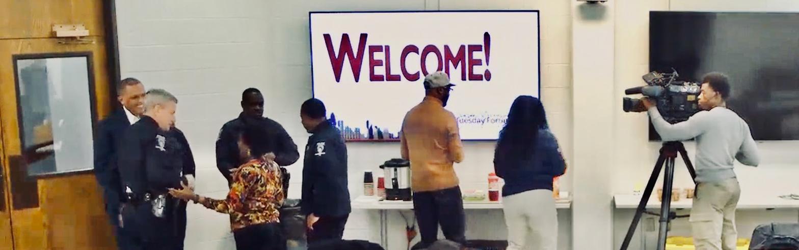 Co-convenor Jackie Edwards Walton welcomes CMPD officers and Chief Johnny Jennings to the Forum on Nov. 11. The big screen is a cool welcome; the coffee posts are hot stuff.